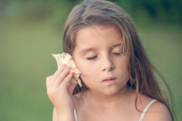 A girl listens to a seashell