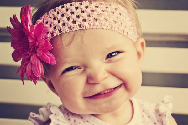 A little girl in a headband with a flower. Portrait