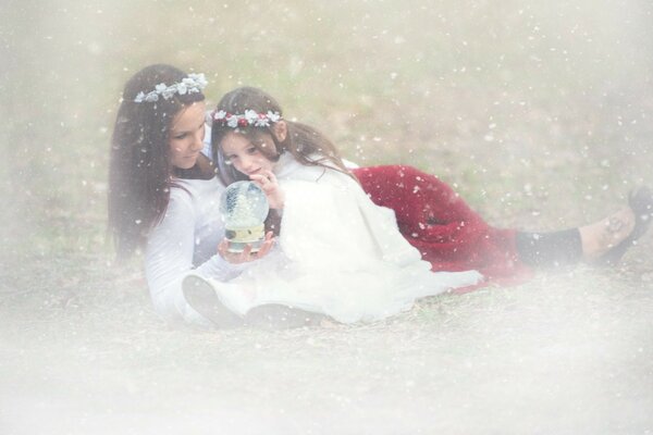 Mom and daughter watch a snow globe