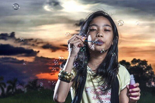 The girl blows soap bubbles