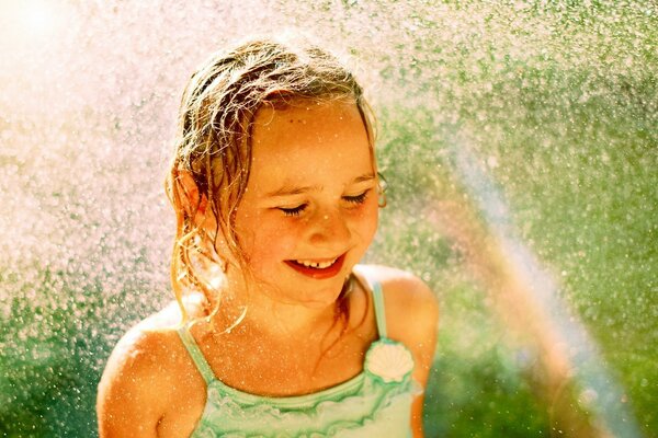 Niña bajo la lluvia se regocija en el arco iris