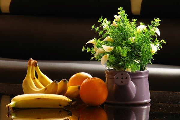 Ao lado de um buquê de flores estão bananas e laranjas