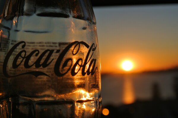 The image shows Coca Cola beer and a sunset