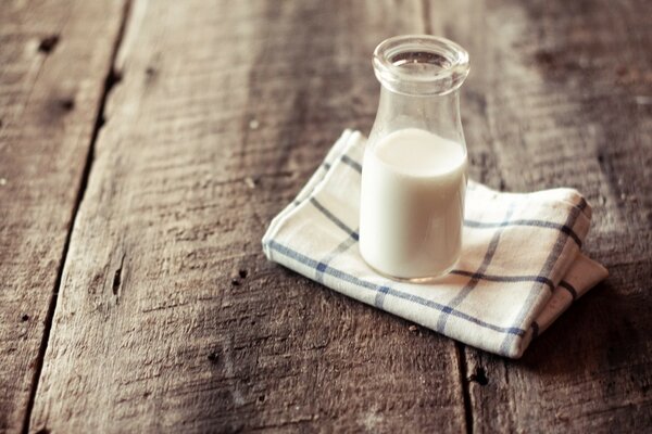 Aile en verre de lait avec une serviette en Lin dans une cage sur une vieille table de planches