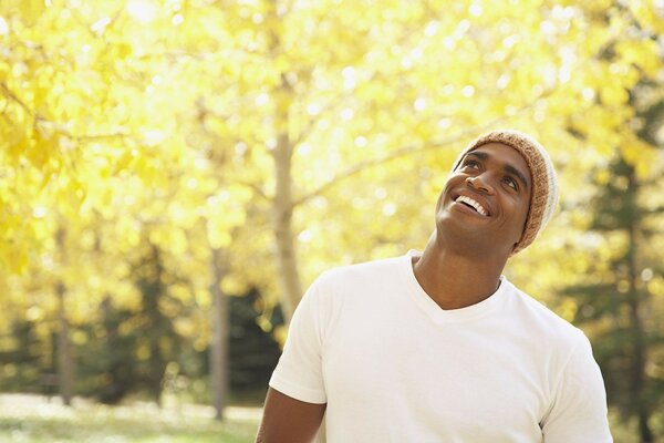 El hombre sonriente en el bosque de otoño