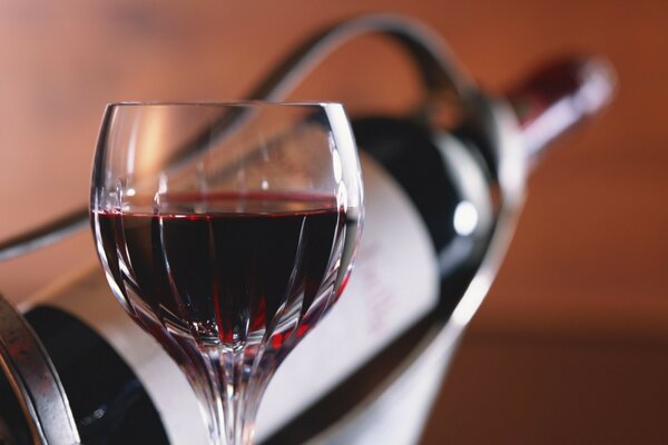 A glass of red wine on the background of a bottle