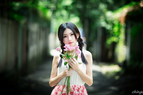 Chica asiática con flores de color rosa al aire libre