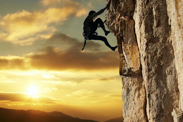 Climber on a steep cliff against the sunset