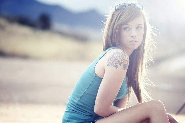 A girl in a blue top sitting on the beach