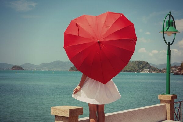 A girl with a red umbrella in the shape of a heart