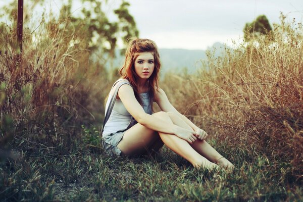 A red-haired girl sitting on the grass