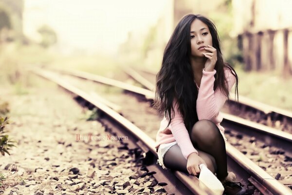 Ragazza in posa sul binario della ferrovia ragazza con cappello di paglia sul prato