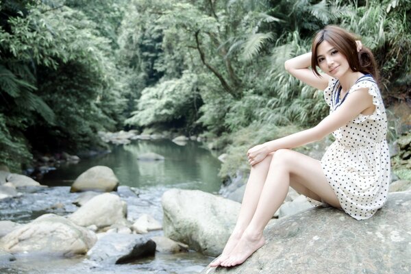 Beautiful girl by the stream in the forest