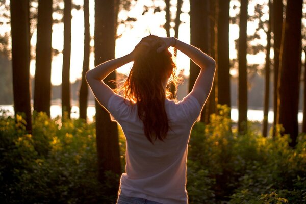 A girl stretches in the woods at dawn