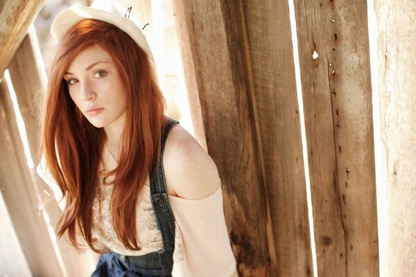 A girl with red hair in a light summer hat