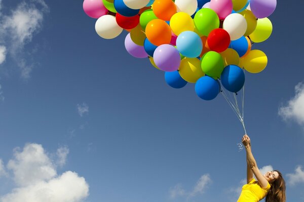 Fille tenant des boules multicolores sur fond de ciel