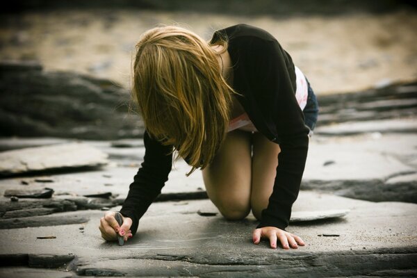 Chica joven dibuja en una piedra