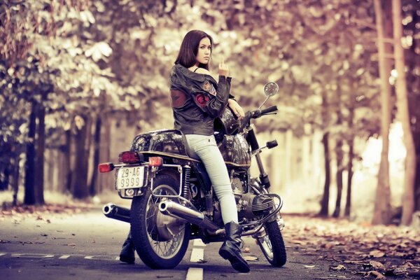 Chica joven en una motocicleta en el bosque