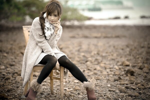 Fille assise sur une chaise près de l océan