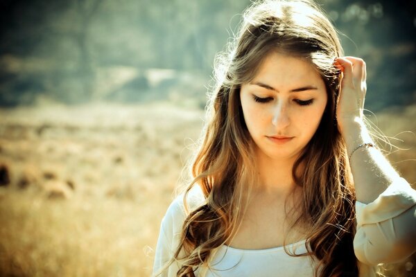 The girl looks down and walks across the field