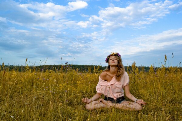 A girl in the lotus position in the middle of a field