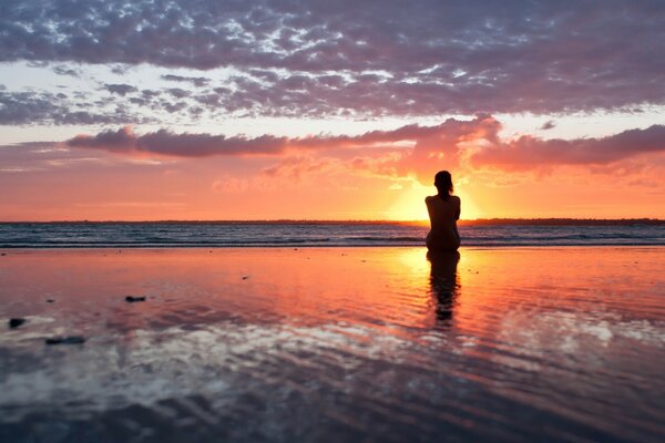 Silhouette einer Frau bei Sonnenaufgang im Wasser