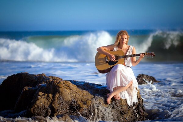 A girl with a guitar on the seashore