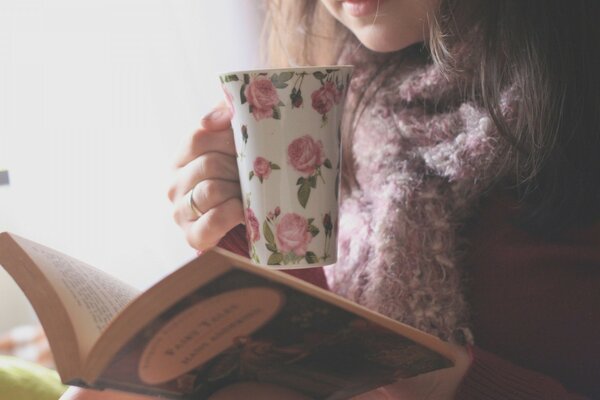 Menina lendo um livro e bebendo chá