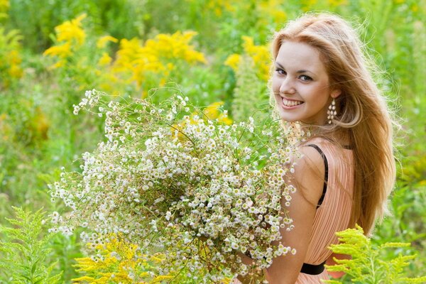 Menina sorridente com um buquê de flores silvestres