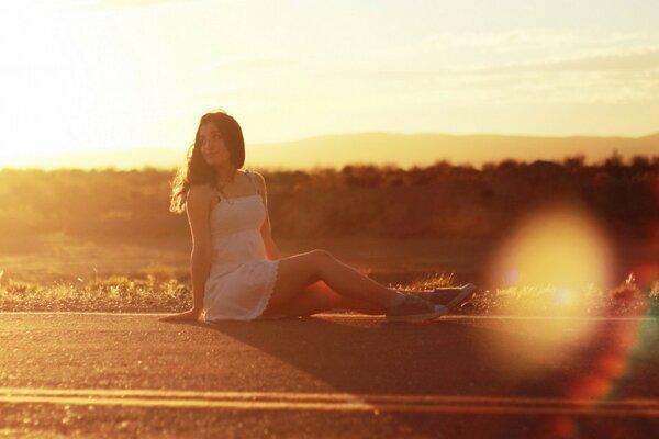 一个女孩坐在路上对着夕阳