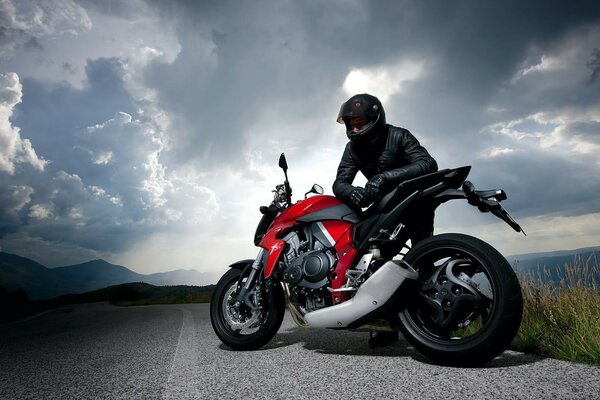 Biker with a motorcycle on the background of clouds