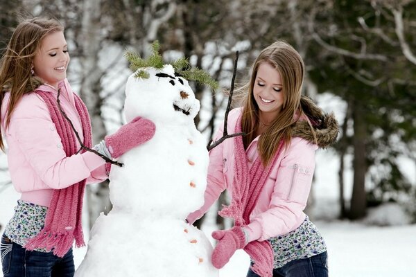 Gemelos esculpen juntos un muñeco de nieve