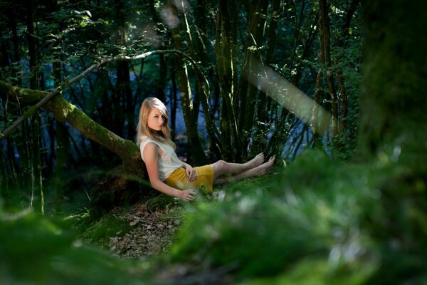 A beautiful girl is sitting by the pond in spring