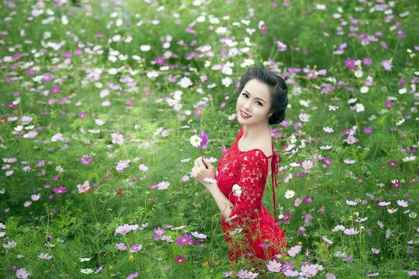 A girl in a red dress stands in flowers