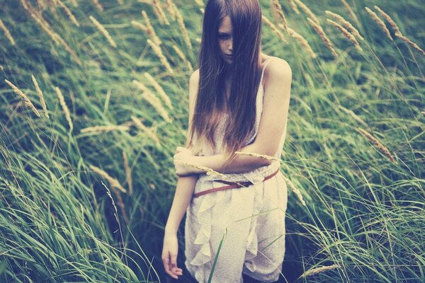 Girl with long hair in the grass in summer