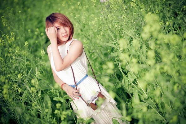 A girl in a field in the grass with a camera