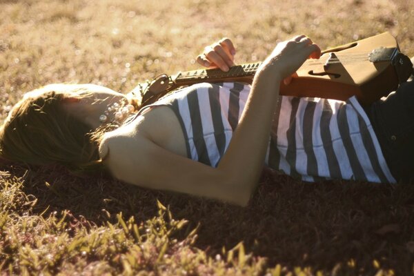 Romántico con un instrumento en la hierba bajo el sol