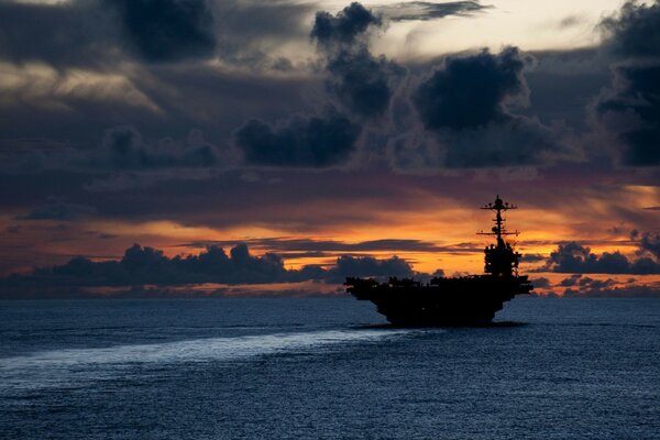 A warship sails at dawn