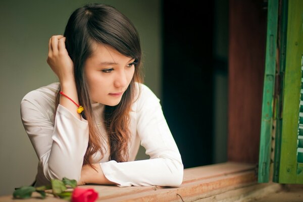 Fille triste a une chambre avec une rose