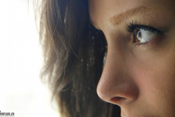 A girl with brown eyes in profile looks into the distance