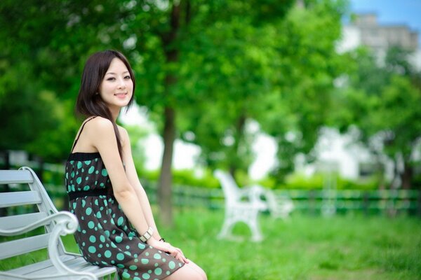 A girl in a sundress on a bench in the park