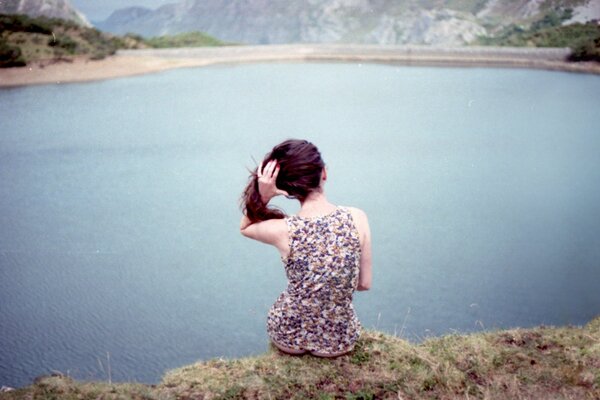 En la orilla del lago se sienta una chica