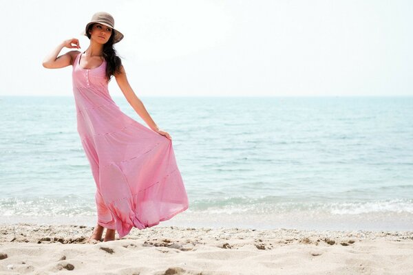 Ein Mädchen in einem rosa Kleid geht am Meer entlang