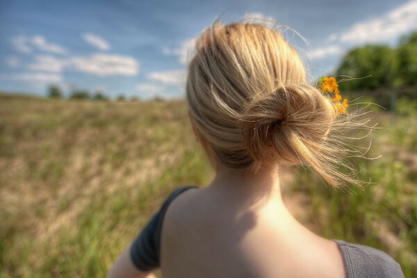 A girl with straw-colored hair and an open back in summer in nature