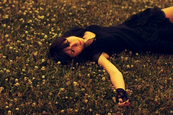 A girl in black is lying on the lawn