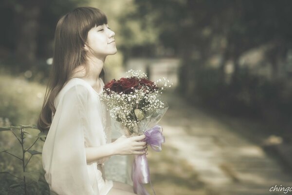 A girl in nature with a bouquet of flowers