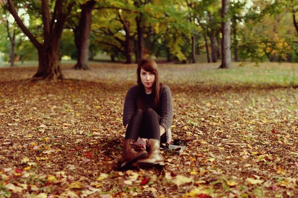 Fille dans le parc parmi les feuilles mortes