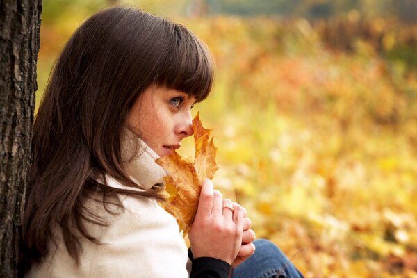 A girl holds autumn leaves in her hands