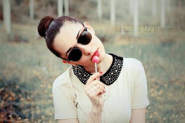 Chica en gafas de sol y con rosa Lollipop