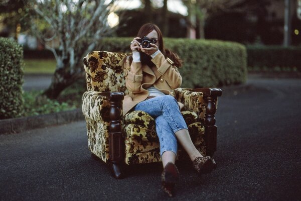 Mädchen Fotograf in einem Sessel mitten im Park